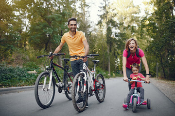 Fototapeta na wymiar Family in a park. People with a bicycle. Parents with little daughter.