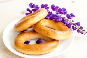 Sweet bagels and tender lupine flowers. Light composition with bright and purple flowers. A tender and romantic morning.