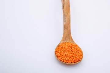 View of pile of red lentils in wooden spoon.
