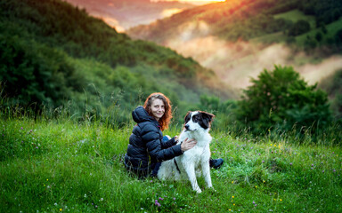 Naklejka na ściany i meble woman and dog in amazing summer landscape at sunset