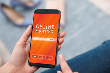 Woman holding smartphone with online shopping website on screen indoors, closeup