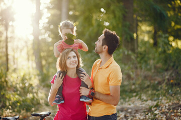 Fototapeta premium Family with cute little daughter. Father in a yellow t-shirt. People walks in a park.