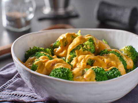 steamed broccoli with melted cheddar cheese sauce in bowl