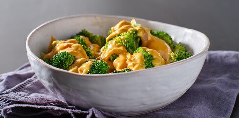 steamed broccoli with melted cheddar cheese sauce in bowl