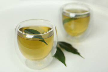 Aromatic green tea and leaves on white table
