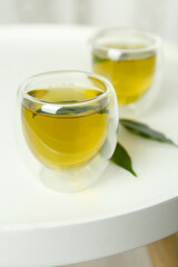 Aromatic green tea and leaves on white table