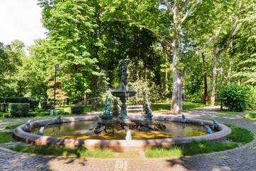 Vrsac, Serbia - June 04, 2020: Part of the fountain in the city park in Vrsac. Hiking trail through the alley in the city park.