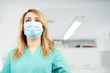 Mujer dentista con mascarilla y equipo de protección individual, EPI, garantizando la máxima...