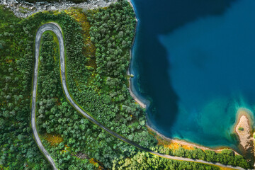 Aerial view serpentine road and forest with sea drone landscape in Norway above trees and blue sea...