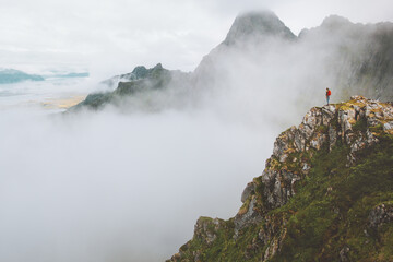 Man traveler in foggy mountains on rocky cliff edge solo travel active lifestyle outdoor adventure vacations in Norway