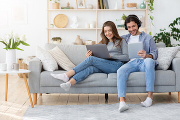 Fototapeta premium Young family spending weekend at home, using gadgets
