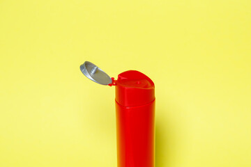 Red bottle with gel shampoo or liquid soap on a yellow background