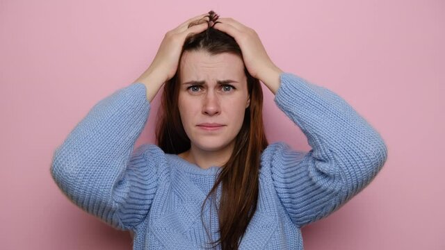 Nervous puzzled woman grabs head, has terrible pain, realizes something very awful, look scared, anxious about making mistake, expresses desperate emotions, isolated on pink background. Bad feelings