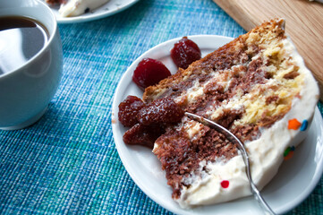 Chocolate sponge cake with cream  on a white plate and a cup of coffee