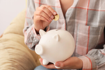 Obraz na płótnie Canvas Woman putting money in piggy bank, closeup