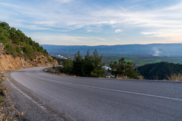 Empty asphalt road going up from the city to the mountain