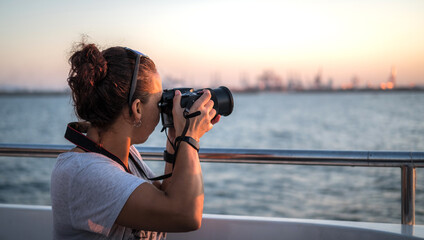 woman traveler on a ship watching the sunset seascape, with bridge camera photo for travel