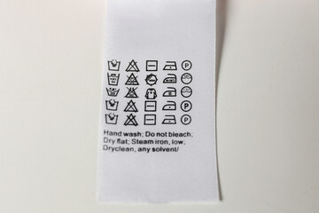Clothing label with care symbols on white background, top view