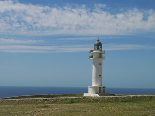 Fototapeta na wymiar Seascape with the white lighthouse in Cap de Barbaria, Formentera island, Spain - blue sky with horizontal clouds