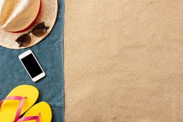 Fototapeta na wymiar Summer vacation composition. Flip flops, and smartphone on sand background. Travel vacation concept. Summer background. Border composition made of towel