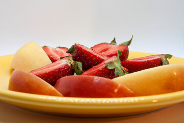 
bright juicy slices of berries and fruits on a plate close-up on a white background