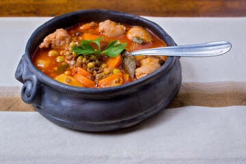 Traditional clay pot containing a lentil stew - tablecloth