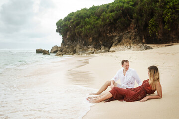 Lovely couple of lovers on the beach of the ocean on a background of mountains