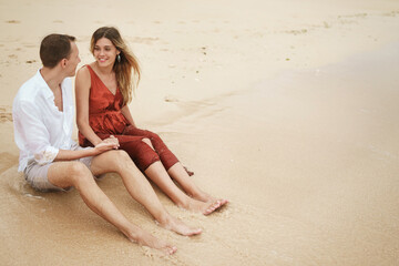A pair of young lovers sitting on the ocean coast