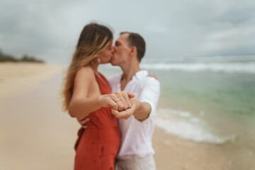 Beautiful engagement ring and a young couple by the ocean