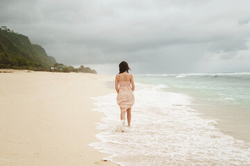 Beautiful woman on the beach of Bali on a background of mountains and the ocean