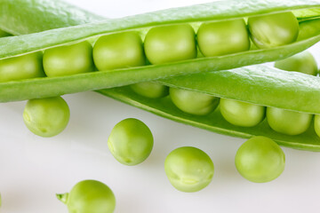 Pods of green peas with pea leaves and flowersd on a white background. Organic food.