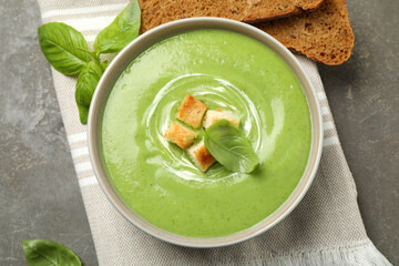 Tasty homemade zucchini cream soup served on grey table, flat lay