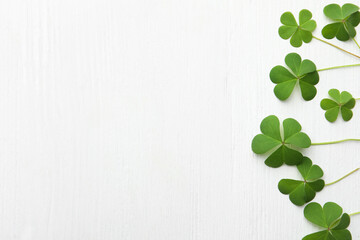 Clover leaves on white wooden table, flat lay with space for text. St. Patrick's Day symbol