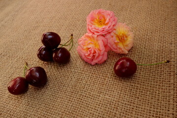 Peach color roses and red cherries on burlap cloth