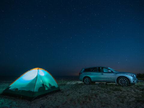 the car and illuminated tent on the beach in hight scene under star sky with copy space