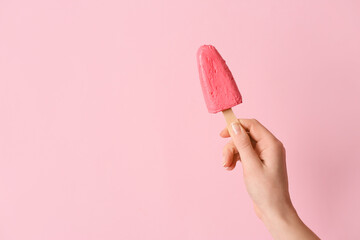 Hand with tasty strawberry ice cream on color background