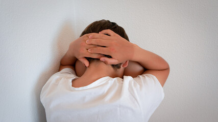 Teenager guy sitting in the corner with hands holding his head, victim concept