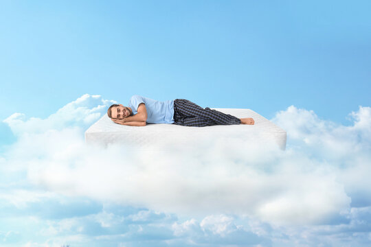 Young man lying on mattress in clouds