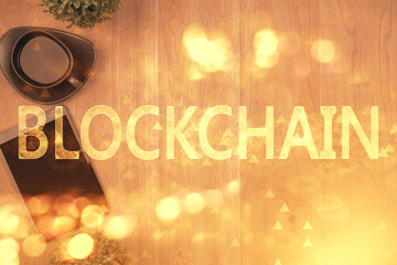 Double exposure of blockchain theme hologram over table with phone. Top view. Crypto technology...