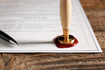 Document with notary public wax seal on table, closeup