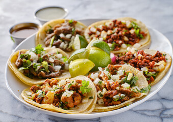 platter of mexican street tacos with carne asada, chorizo, and al pastor in corn tortillas