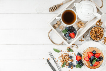 Healthy breakfast with american pancake, granola, fruits, berries on white background.
