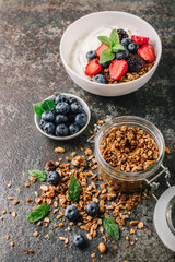 Healthy breakfast with granola, yogurt, fruits, berries on dark metal background. Summer homemade breakfast.