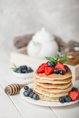 Classic american pancakes with fresh berry on white wood background. Summer homemade breakfast.