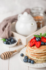 Classic american pancakes with fresh berry on white wood background. Summer homemade breakfast.