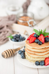 Classic american pancakes with fresh berry on white wood background. Summer homemade breakfast.