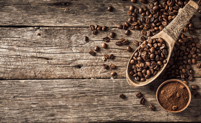 Coffee beans in wooden spoon on wood background.