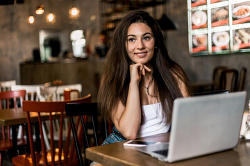 Business woman working on a laptop and drinking coffee in a cafe.