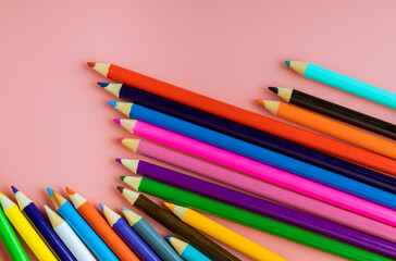 School supplies colored pencils top border on a pink background