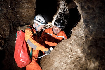 Two men, strong physique, explore the cave. Men dressed in special clothes to pass through the cave...